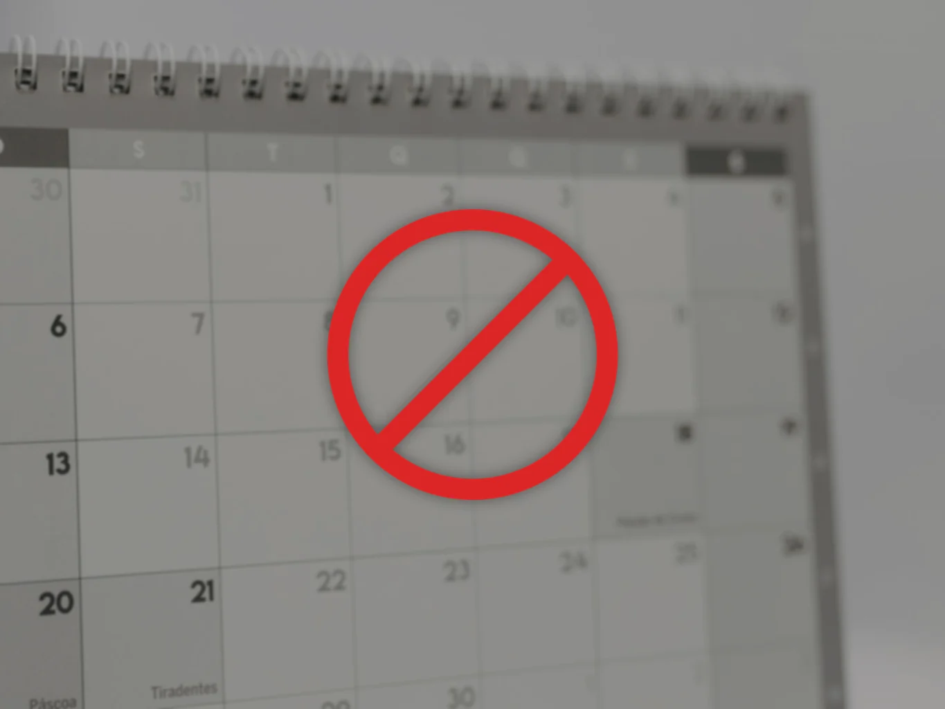 A red circle-and-slash cancellation symbol centred over a softly blurred desk calendar page