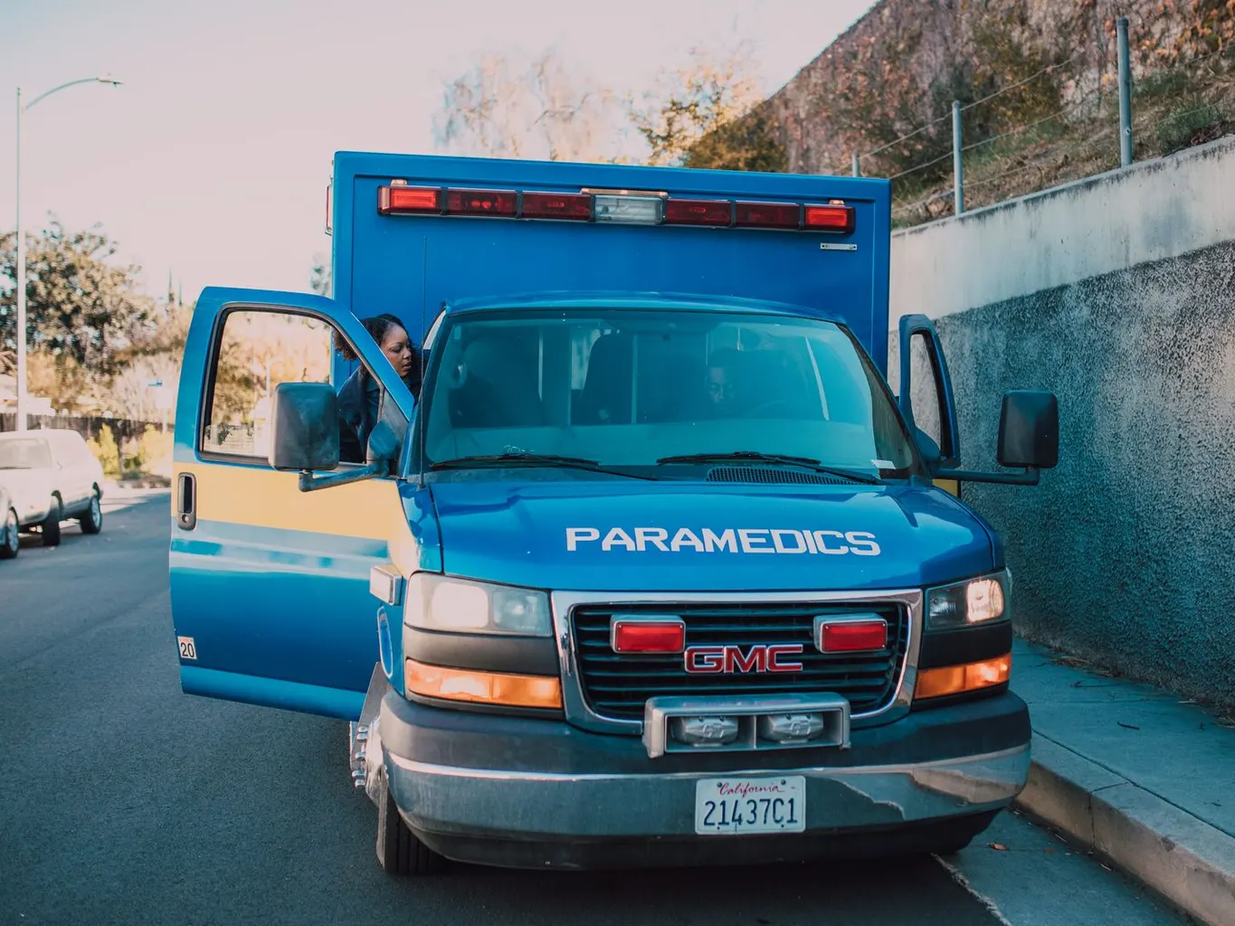 A blue GMC paramedics ambulance parked on a street with its door open