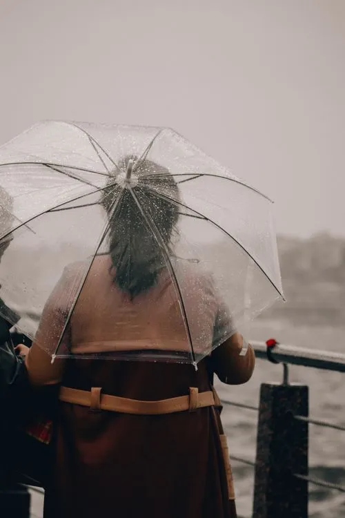 Woman with transparent umbrella on a rainy urban waterfront
